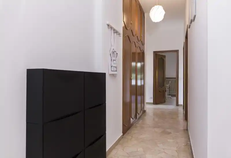 Ingresso/corridoio luminoso e curato con armadi a muro in legno, pavimento piastrellato e una lampada a sospensione moderna — perfetto per una buona prima impressione.