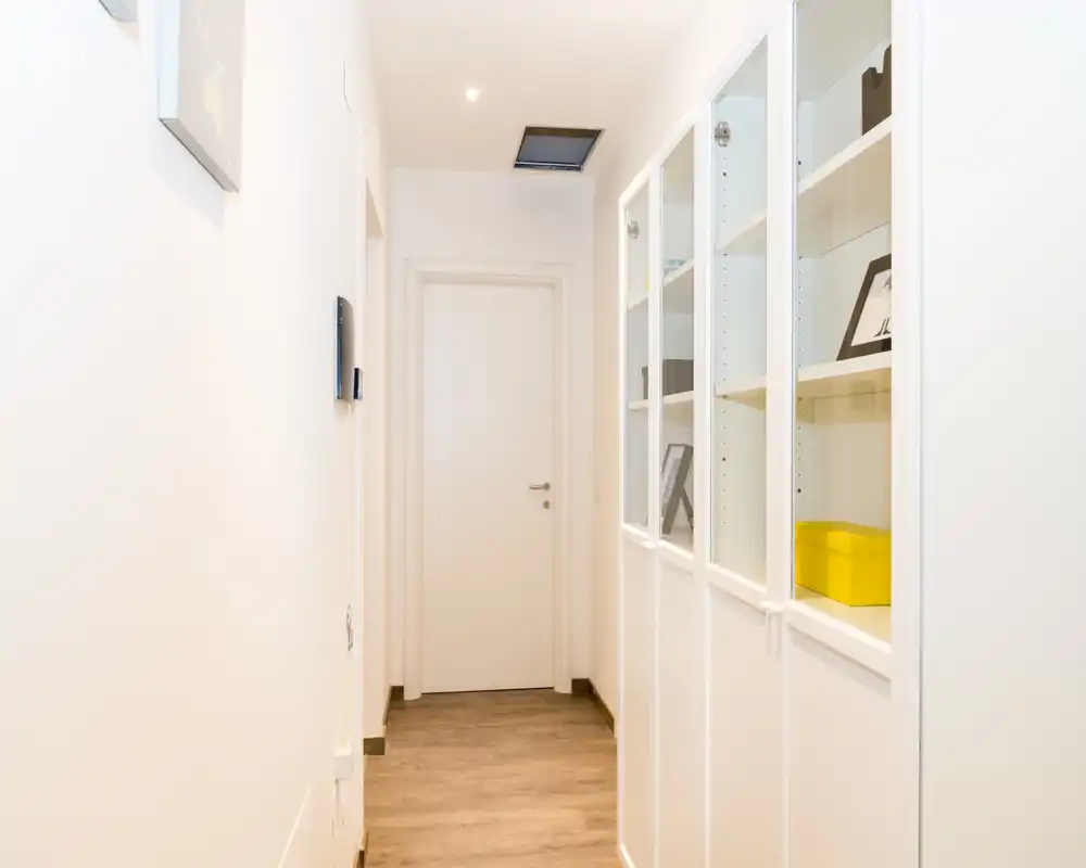 Corridoio luminoso e minimale con armadi a vetro incorporati e porta chiusa in fondo: ingresso moderno e ordinato adatto a un annuncio immobiliare.