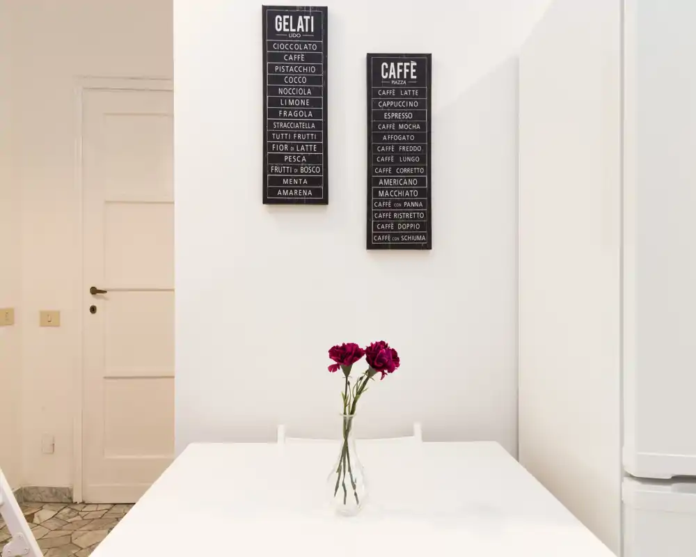 Minimal, bright dining corner with a white table, vase with flowers and wall art — clean and inviting for meals.
