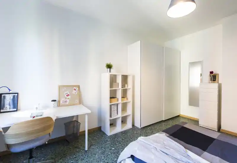 Bright, modern bedroom with a neatly made bed, a workspace with desk and chair, and built-in storage; ideal for students or professionals seeking a minimalist room.