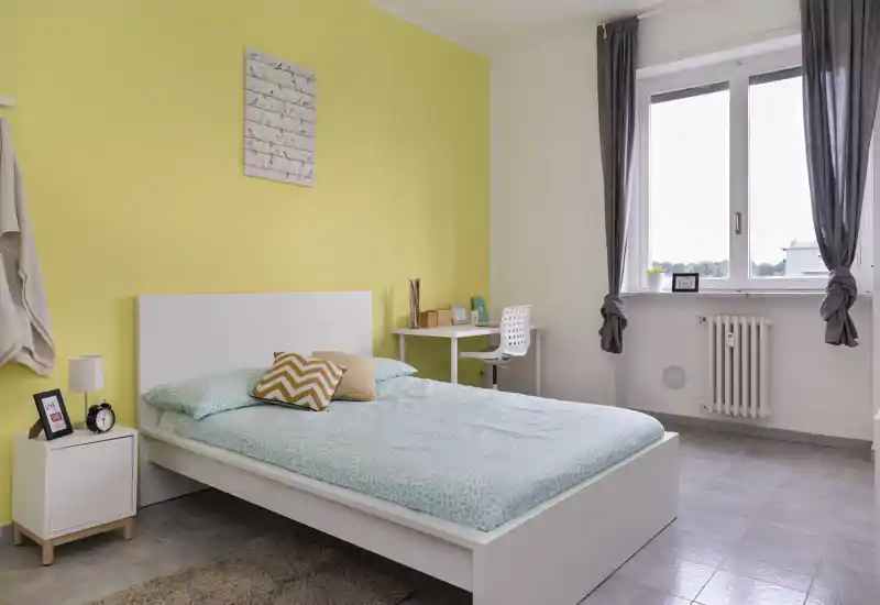 Bright twin-bedroom with two single beds, decorative cushions and large windows providing natural light — ideal for short stays and shared guests.
