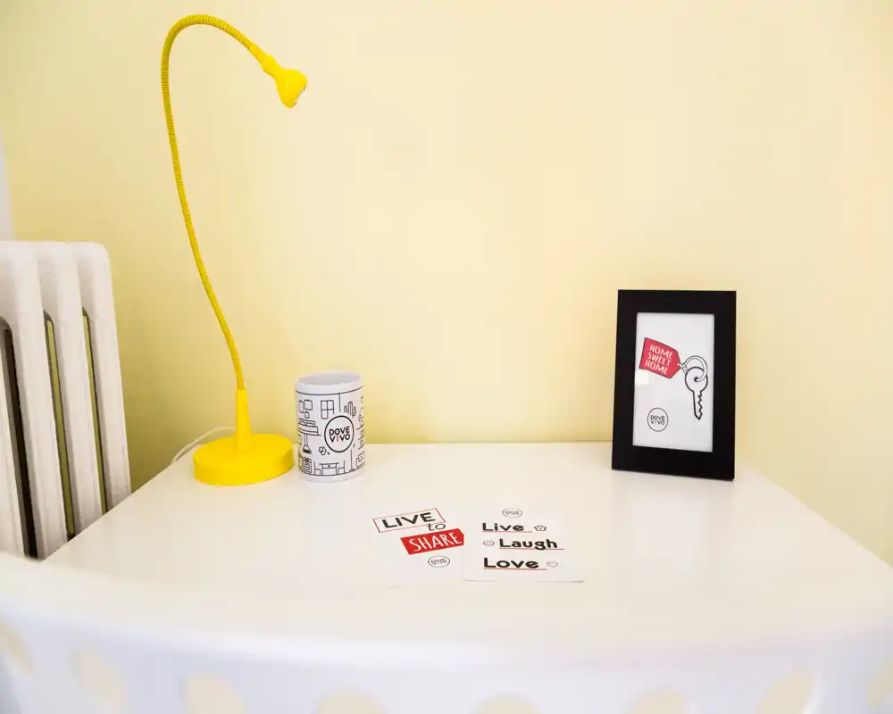 Petit coin salon soigné avec une table blanche, une lampe de bureau jaune, un cadre et des cartes décoratives — une prise de vue mettant en valeur un coin cosy du séjour.
