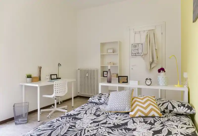 Dormitorio luminoso y ordenado con cama doble estampada, cojines decorativos y una pequeña zona de escritorio — ideal para una estancia cómoda o teletrabajo.