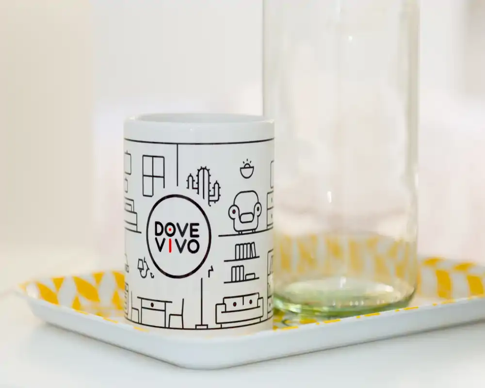 Foto en primer plano de una taza de marca sobre una bandeja decorativa junto a un vaso; imagen de detalle adecuada para destacar accesorios o decoración.