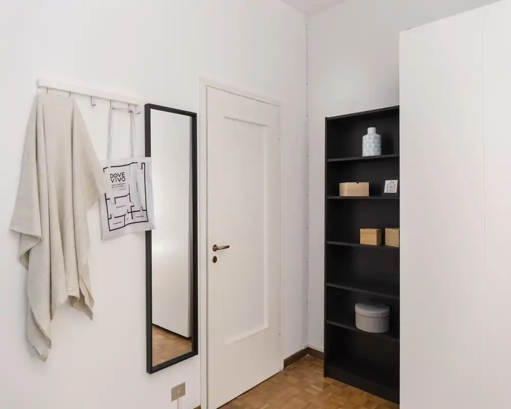 Entrée lumineuse et minimaliste avec patère murale, miroir pleine‑longueur et étagère — un hall d'entrée simple et accueillant.