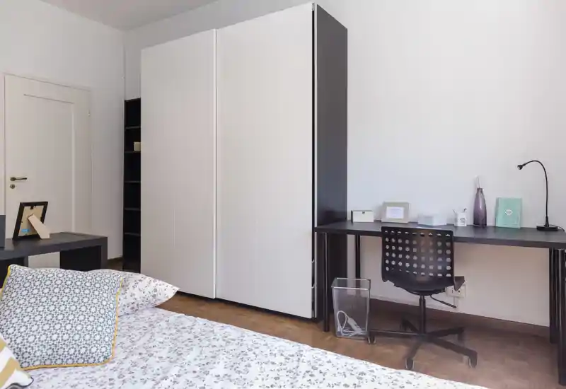 Chambre moderne et lumineuse avec lit à motifs, grand placard et un bureau soigné — idéale pour un séjour confortable.