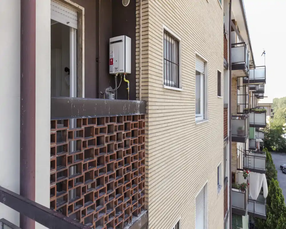 Vue extérieure d’un immeuble montrant plusieurs balcons et la façade, avec un écran de briques ajourées et des garde-corps métalliques.