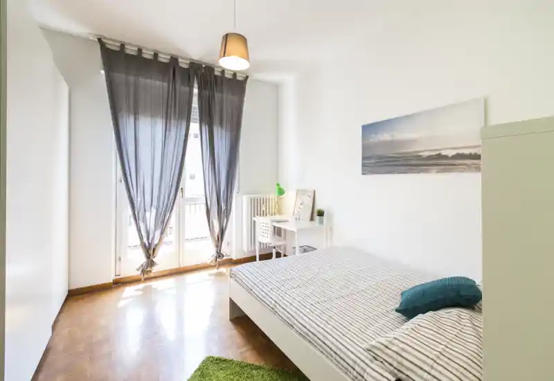 Dormitorio luminoso y bien decorado con cama doble, almohadones y un pequeño escritorio junto a la ventana que aporta mucha luz natural.