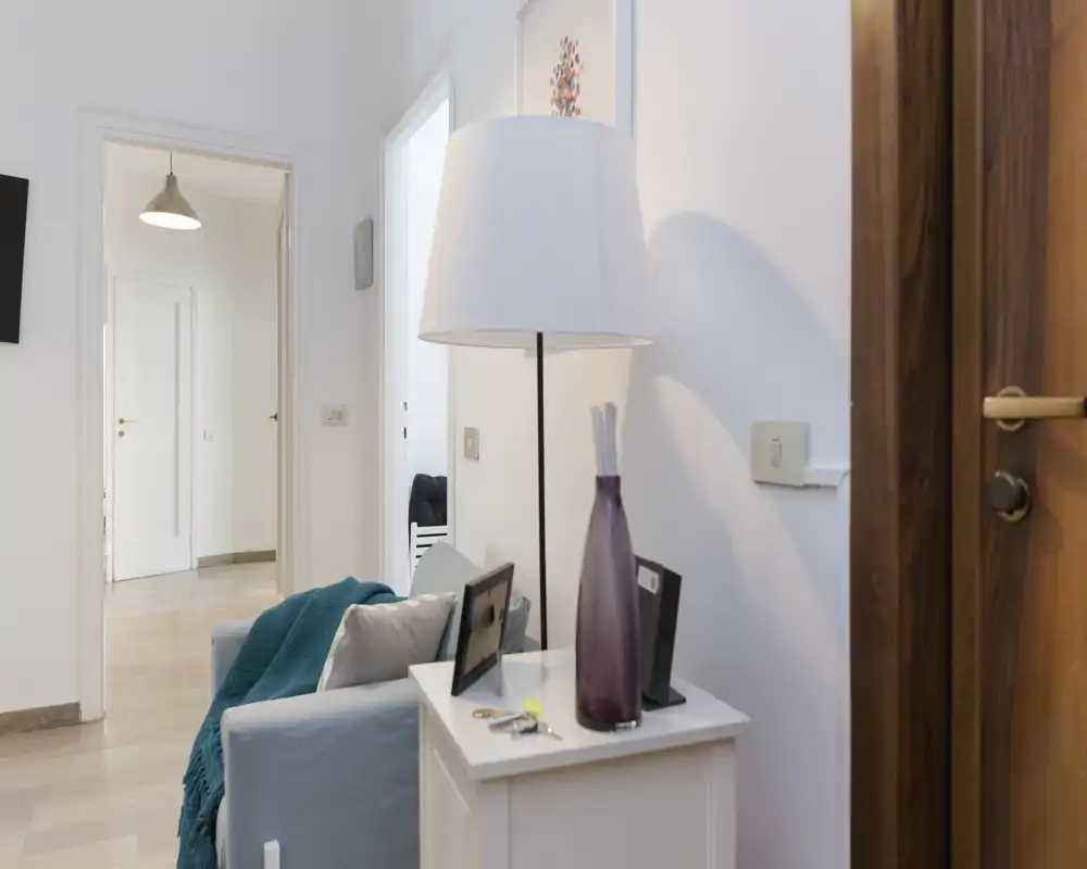 Bright, cozy living area corner with a small sofa, side table, decorative vase and floor lamp — well-styled for a rental listing.