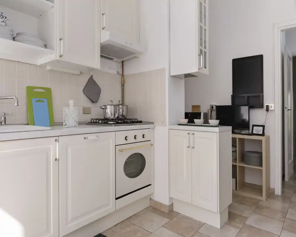 Bright, compact kitchen with white cabinetry, gas hob and integrated oven. Clean counters, stacked plates and a small prep area make it practical for short stays.
