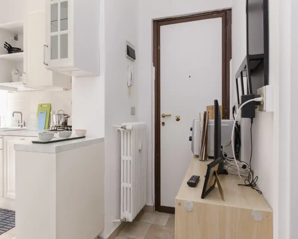 Compact open kitchenette beside the entrance with a small countertop, sink and stove; practical layout ideal for a studio apartment.