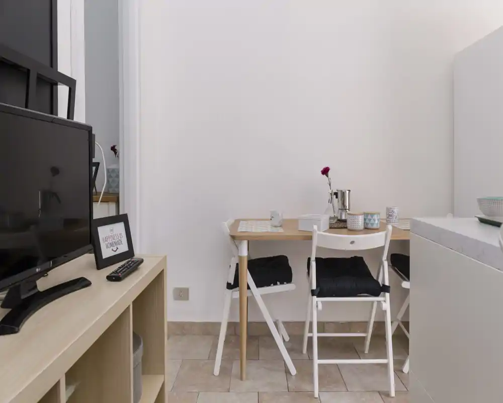 Cozy dining corner with a small wooden table set for two, cushioned folding chairs and simple decorative accents. Bright, tidy and ideal for compact apartment listings.