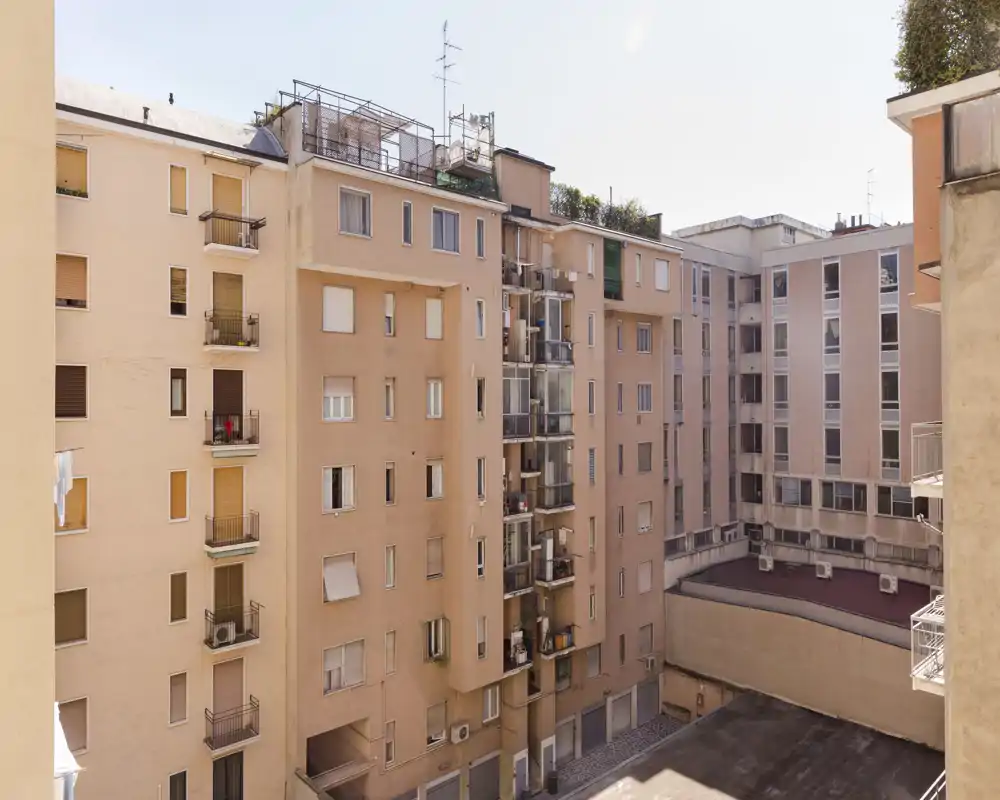 Inner courtyard view showing surrounding apartment façades, balconies and rooftop details; bright daylight and clear architectural details.