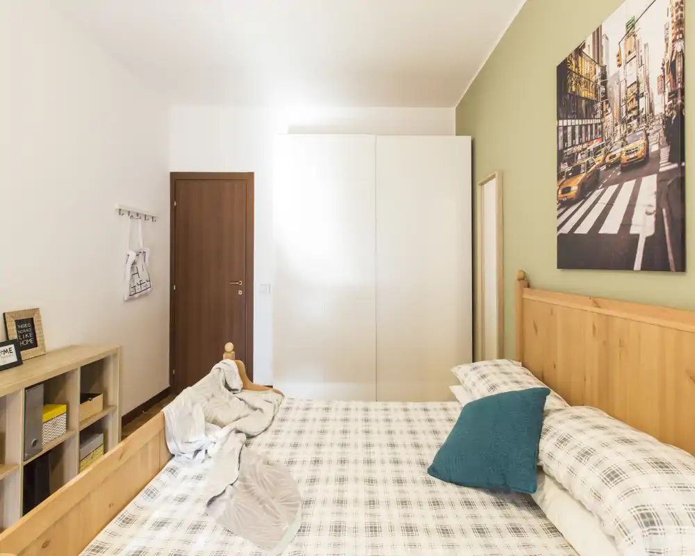 Dormitorio luminoso y bien decorado con cabecero de madera, ropa de cama a cuadros y un gran armario; acogedor y listo para huéspedes.