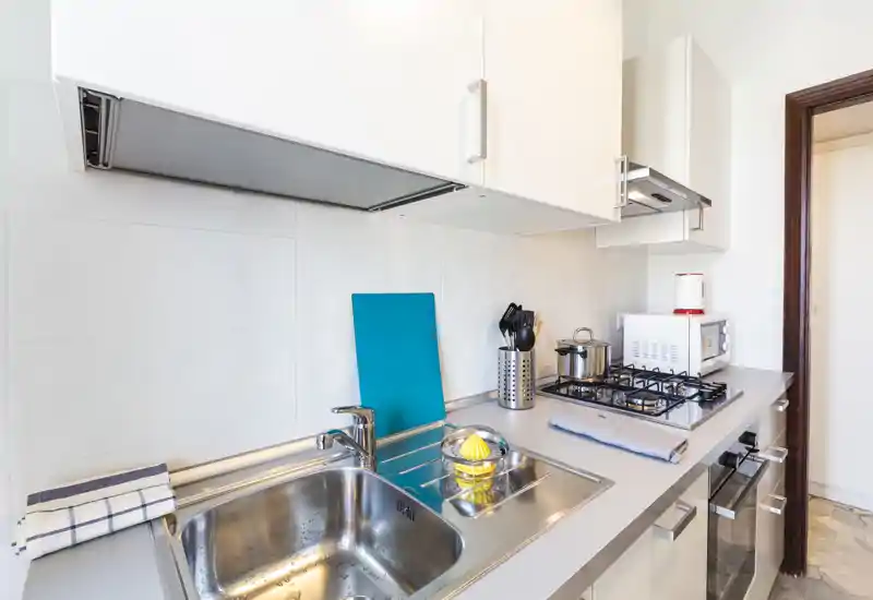 Bright modern kitchenette with stainless steel sink, gas hob, microwave and compact countertop appliances — clean, well-lit and functional space ideal for short-stay rentals.