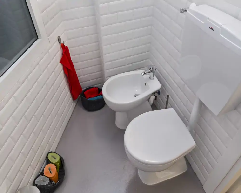 Bagno compatto e moderno con piastrelle bianche a metro, WC e bidet, finiture pulite e luminose — perfetto per annunci di piccoli appartamenti.