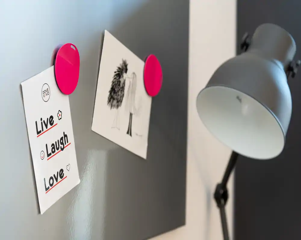 Plano detalle decorativo de una pizarra magnética con dos notas sujetas y una lámpara de escritorio — un elemento de estilismo apto para fotos de detalle en un anuncio.