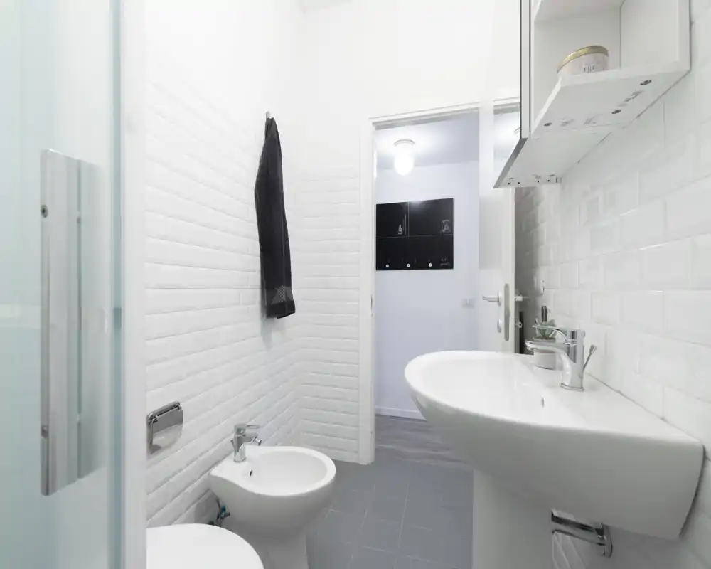 Clean, modern bathroom with white subway tiles, wall-mounted sink and bidet, and a bright, minimalist finish.