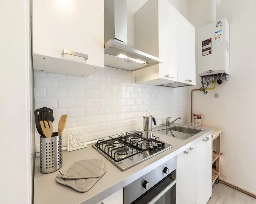 Bright modern kitchenette with a gas cooktop, stainless sink and white subway tile backsplash. Clean, compact layout with cookware and utensils neatly arranged—ideal for small apartments.