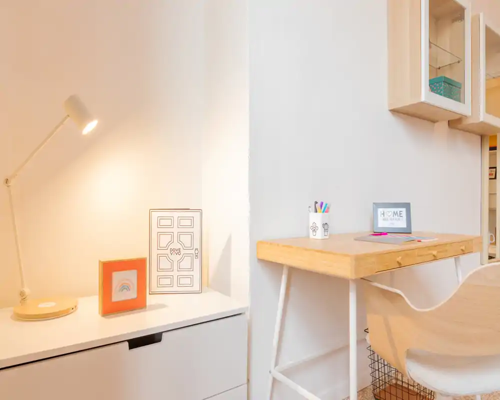 Coin séjour/travail lumineux et minimaliste avec bureau en bois, chaise et lampe chaleureuse offrant une ambiance accueillante et fonctionnelle.