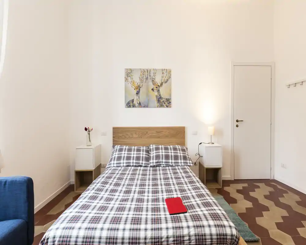 Bright, neatly styled bedroom with a double bed, patterned duvet and bedside tables with lamps and simple wall art.