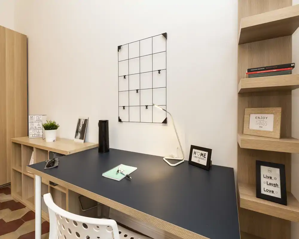 Bright, minimal workspace corner with a large desk, shelving and decorative accents — ideal for focused work or study in a cozy, modern apartment.