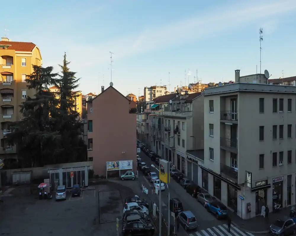 Urban exterior view showing a residential street, parked cars and apartment façades under clear sky—useful for showcasing location and street context.