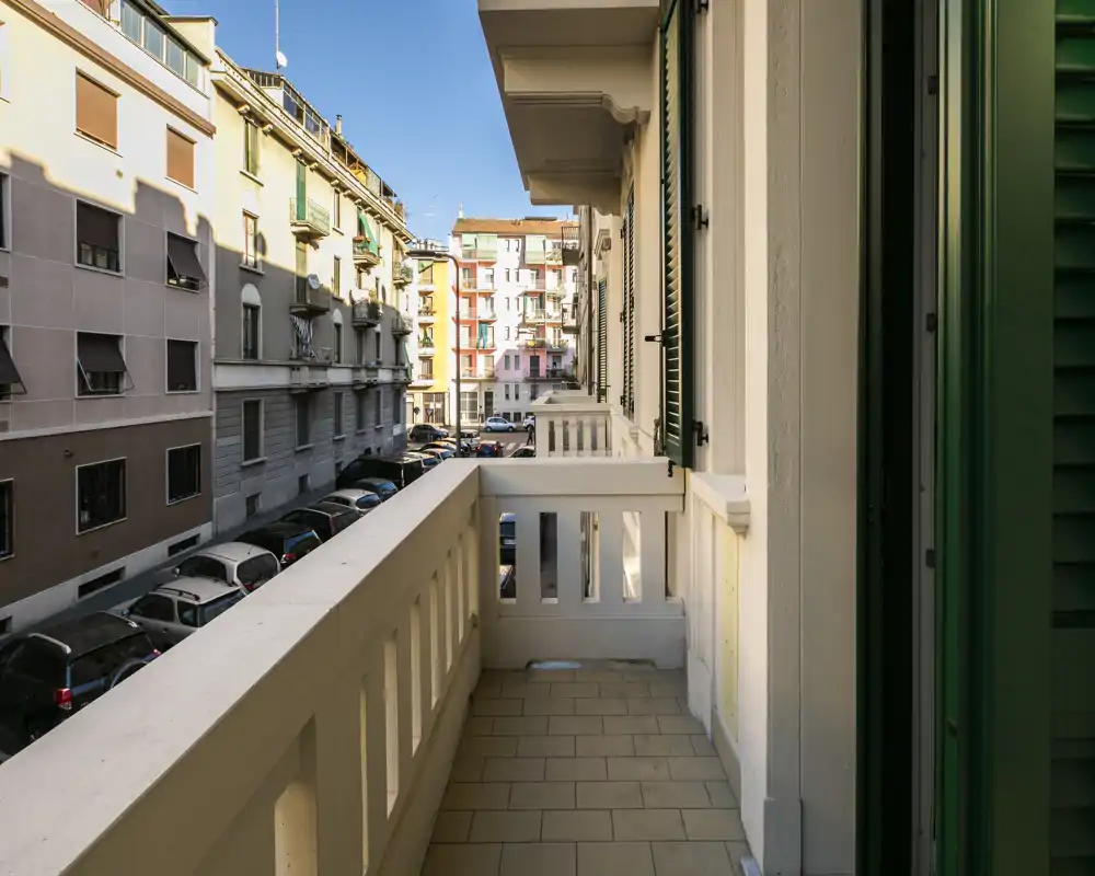 Balcón privado soleado con vistas a una calle tranquila; suelo de baldosas y barandilla clásica que crean un agradable espacio exterior.