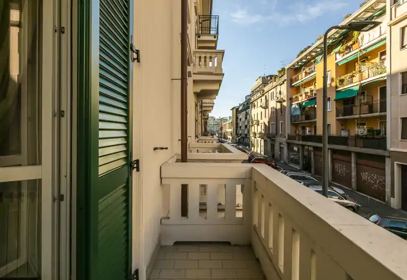 Balcón privado soleado con vistas a una calle urbana tranquila y fachadas clásicas — perfecto para el café de la mañana.