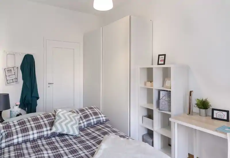 Bright, modern bedroom with patterned bedding, a large wardrobe and neat shelving; ideal for single or couple stays.