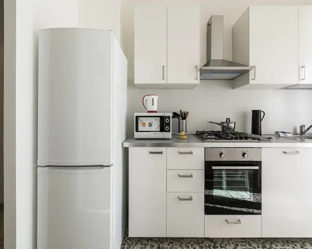 Bright, modern kitchen with white cabinetry, a refrigerator, built-in oven, gas cooktop and countertop appliances—clean, functional space ideal for short-term rentals.