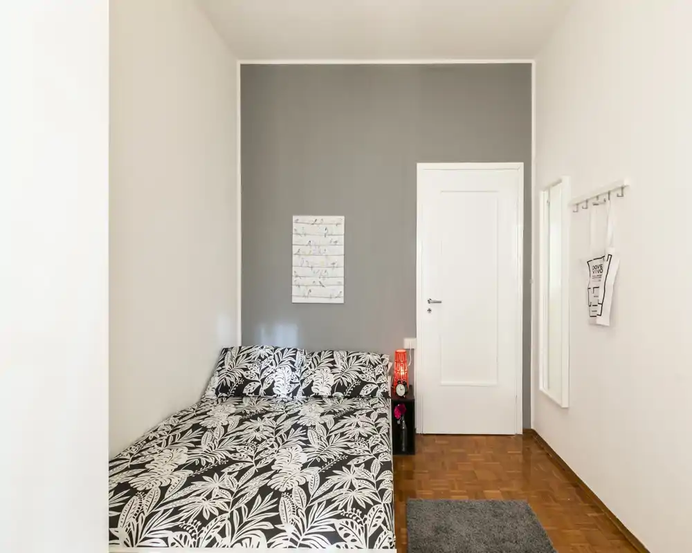 Chambre lumineuse et soignée avec un lit double en linge à motif botanique, une lampe de chevet et une décoration minimale — moderne et idéale pour une annonce.