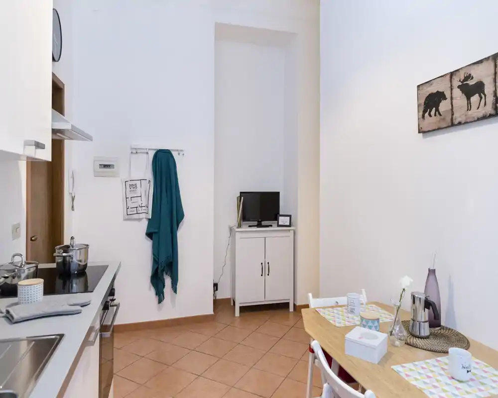 Rincón de cocina luminoso y compacto con placa de cocción, fregadero y una pequeña mesa para dos — ordenado, bien iluminado y acogedor para estancias cortas.
