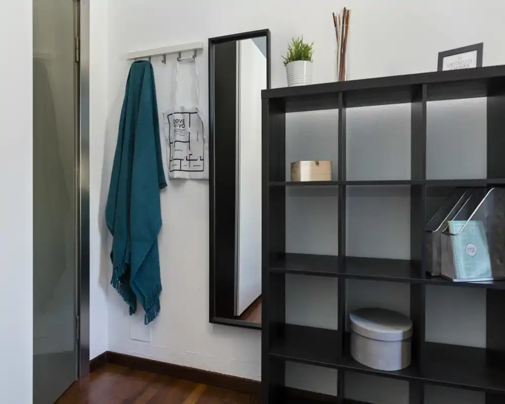 Ingresso elegante con appendini a parete, specchio a figura intera e libreria a cubi — luminoso, ordinato e accogliente.