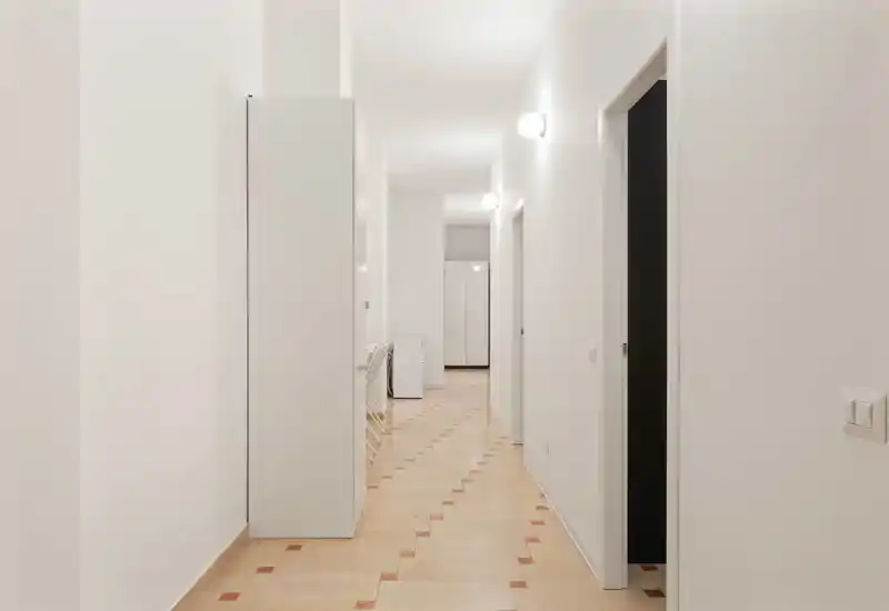 Ingresso/corridoio luminoso e minimale con pareti chiare e pavimento a motivi; passaggio pulito e ben illuminato ideale per mostrare l’area di ingresso.