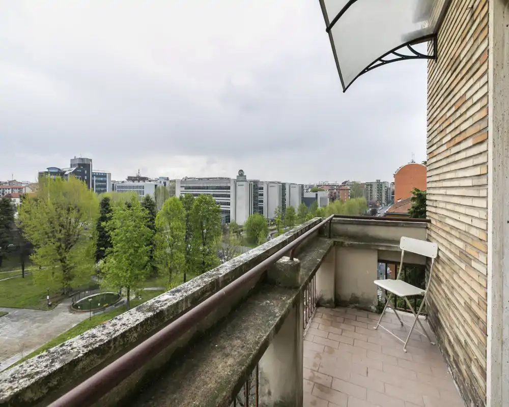 Balcón con vistas a la ciudad y al parque, suelo de baldosa y una pequeña zona para sentarse — ideal para tomar el café por la mañana o relajarse contemplando el verde.