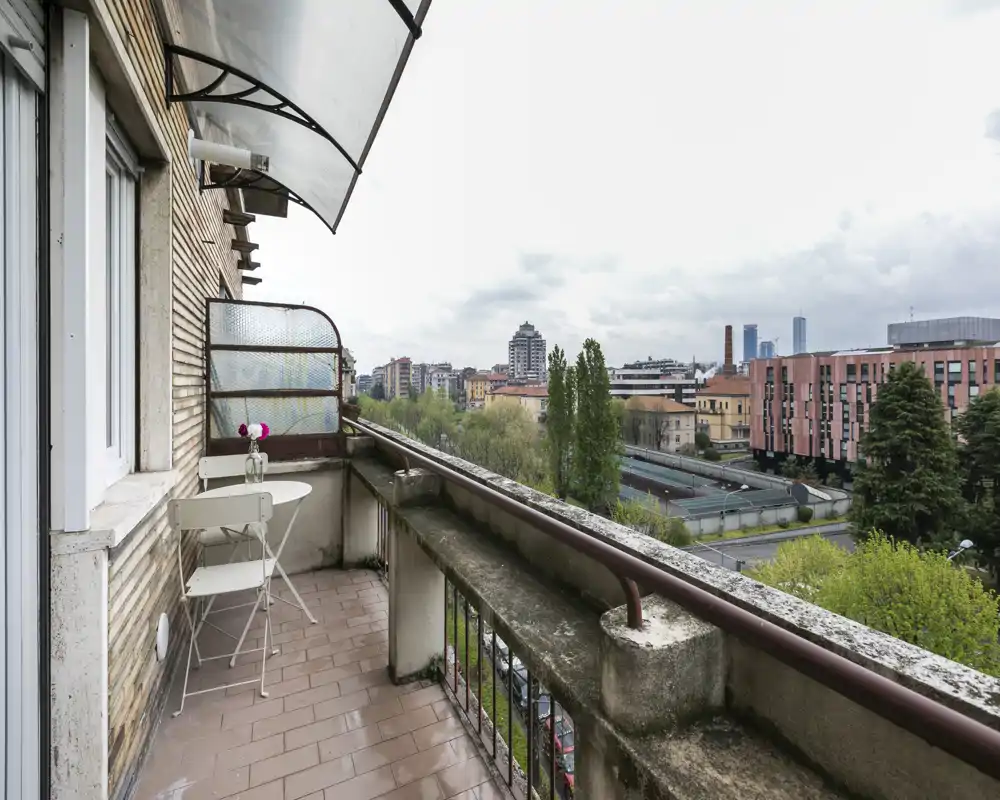 Balcón con mesa y sillas tipo bistró con vistas a la ciudad y áreas verdes — ideal para desayunos o relajarse disfrutando del paisaje.
