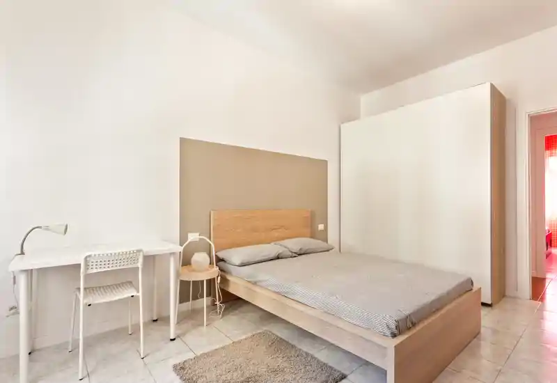 Dormitorio moderno y luminoso con cama doble, cabecero de madera, mesita y escritorio blanco — decoración minimalista y mucha luz natural.