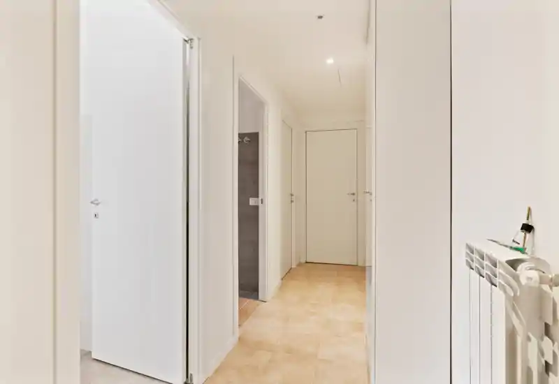 Bright, minimal entrance corridor with tiled floor, white doors and clean lines — ideal as a welcoming hallway space.