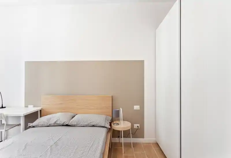 Dormitorio moderno y luminoso con cabecero de madera, cama doble bien hecha, mesita y escritorio — decoración minimalista y relajante, ideal para descansar.