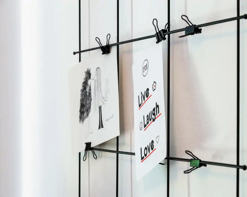 Close-up of a decorative wire grid with clipped prints reading “Live Laugh Love”; this is a detail shot, not a full room view.