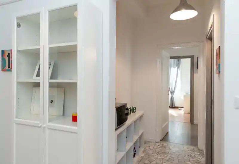 Entrada/pasillo luminoso y ordenado con armarios, lámpara colgante y suelo de baldosas que conduce a otras estancias — excelente primera impresión para un alquiler.
