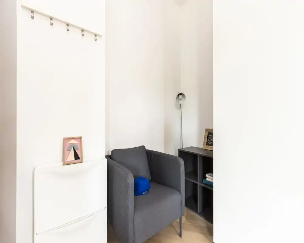 Angolo lettura accogliente con poltrona grigia moderna, lampada da terra e piccolo scaffale — perfetto per un angolo tranquillo nel soggiorno.