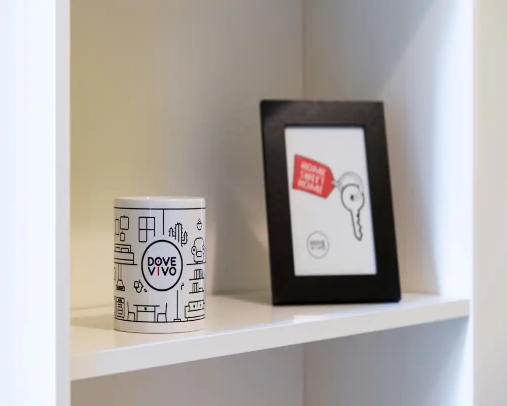 Primer plano de objetos decorativos en una estantería blanca: una lata con marca y un marco. La imagen destaca detalles de estilo y no una habitación concreta.