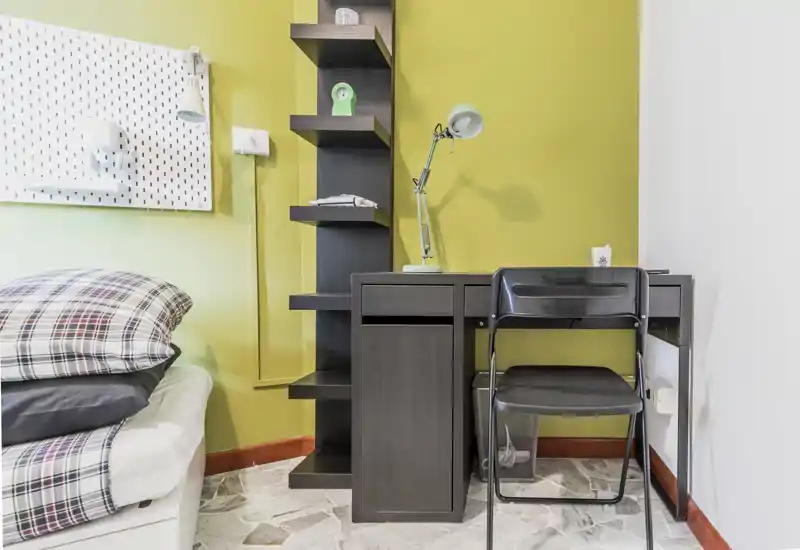 Bright, compact bedroom corner with a visible bed, smart shelving and a small desk — ideal for a student or single renter.