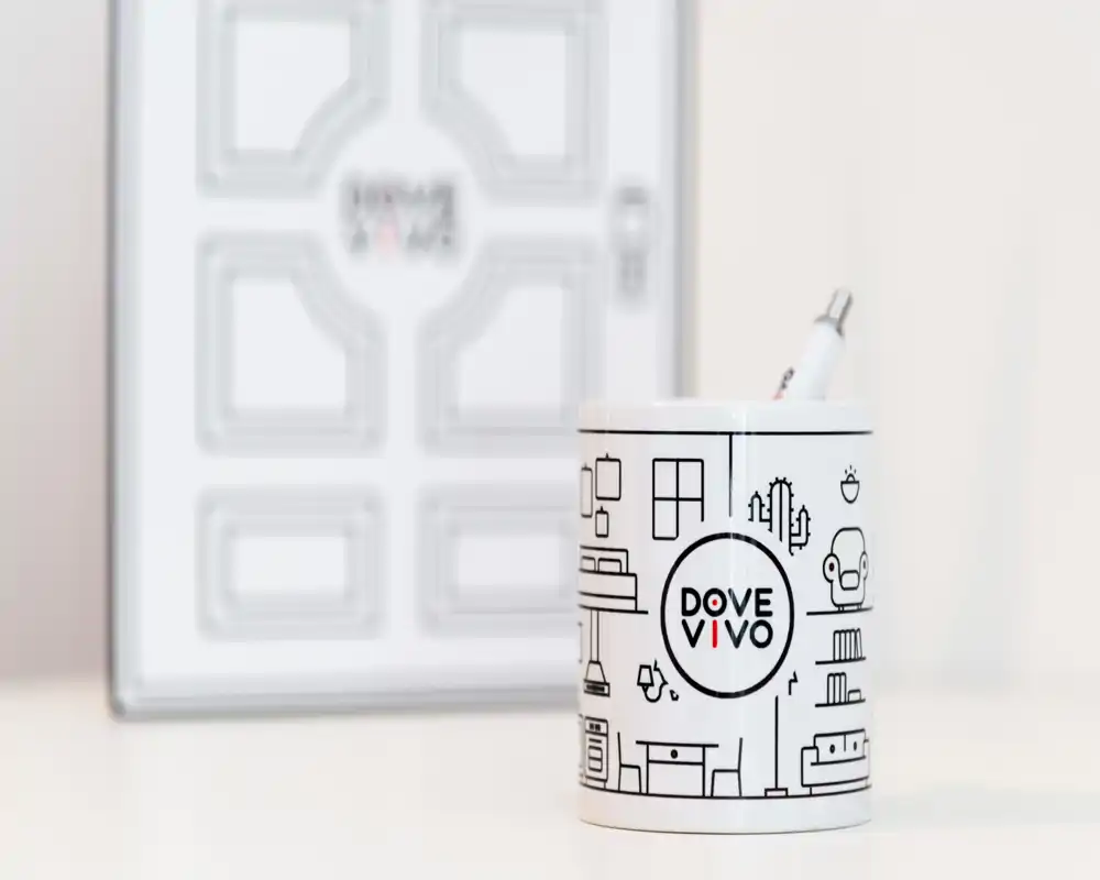 Primo piano di un portapenne brandizzato su una superficie pulita con una cornice sfocata sullo sfondo; l'immagine mette a fuoco un oggetto decorativo, non una stanza specifica.