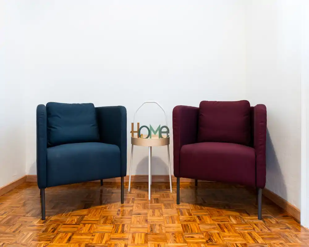 Angolo conversazione compatto e di stile con due poltrone moderne e un tavolino con il décor "HOME": il parquet riscalda l’ambiente e crea un angolo living accogliente.