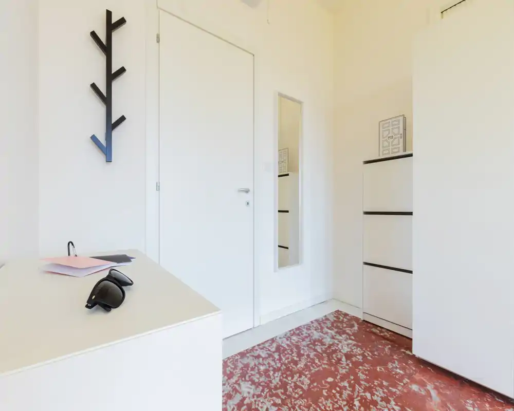 Entrada minimalista y luminosa con perchero de pared, espejo de cuerpo entero y muebles de almacenamiento sobre suelo con diseño.