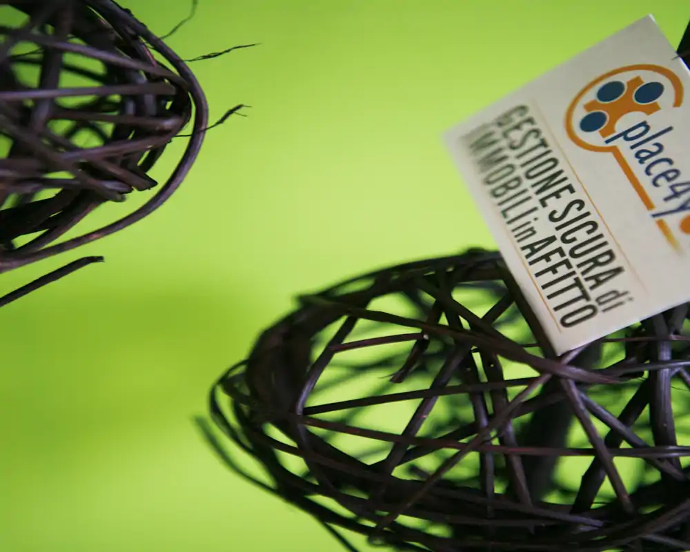 Primer plano de bolas decorativas de mimbre/ratán con una pequeña etiqueta sobre un fondo verde intenso. La imagen es un detalle y no muestra una habitación identificable.