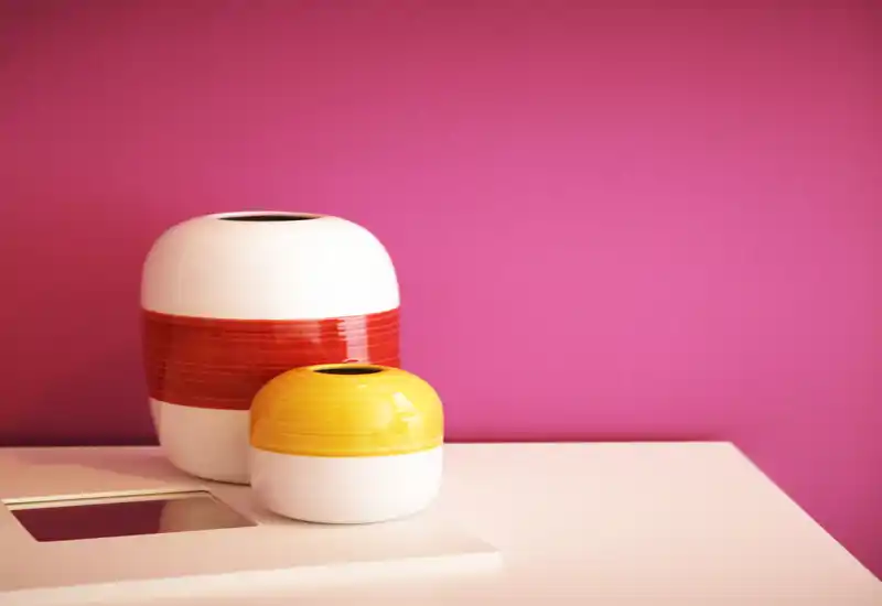 Close-up of decorative ceramic vases on a clean surface against a vivid pink wall; this image highlights styling details rather than a specific room.